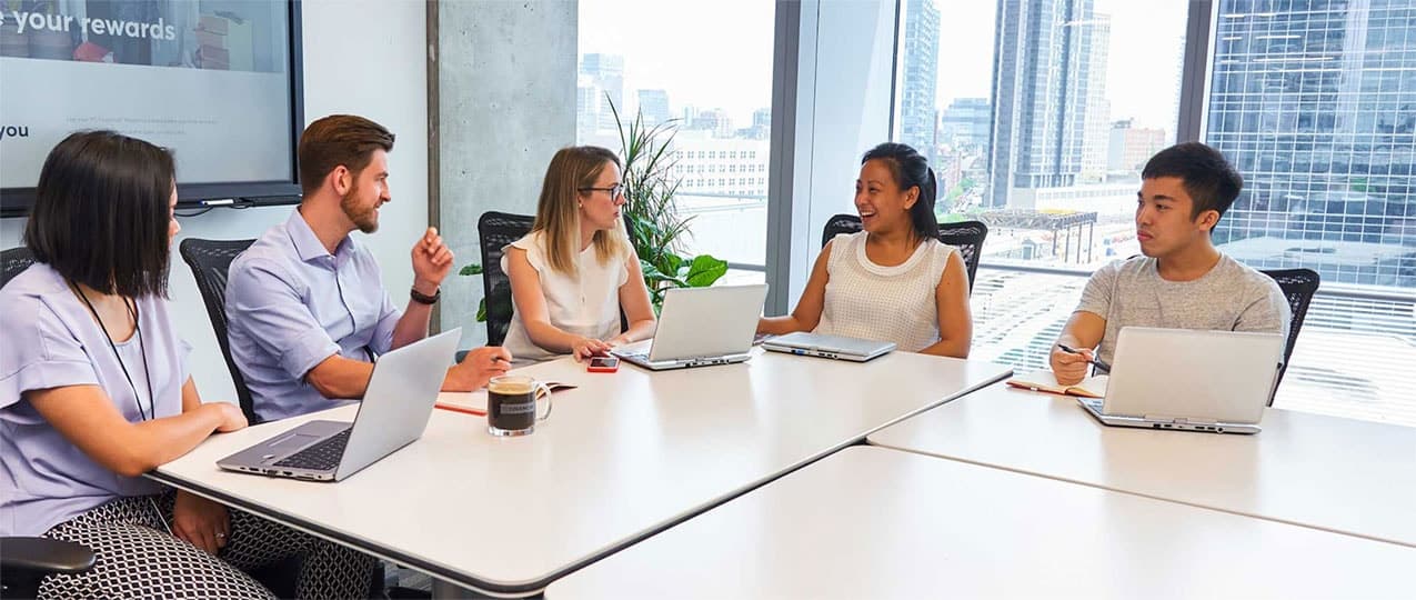 People sitting around at a table using laptops